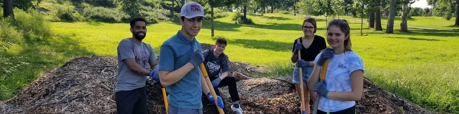 Students standing with shovels around a garden