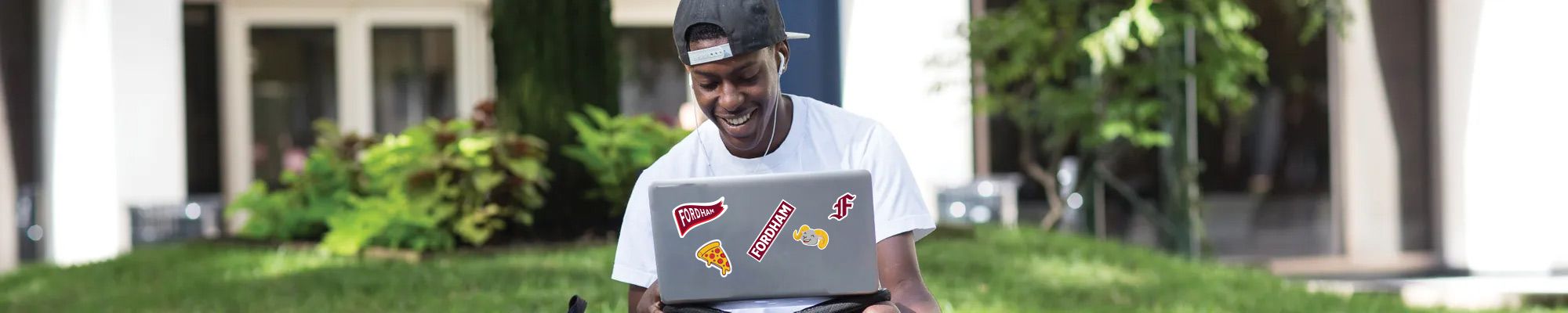 Fordham student on laptop with Fordham stickers