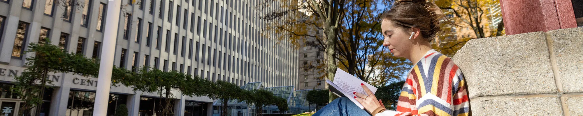 Fordham Student Reading a Book on the Lincoln Center Plaza.