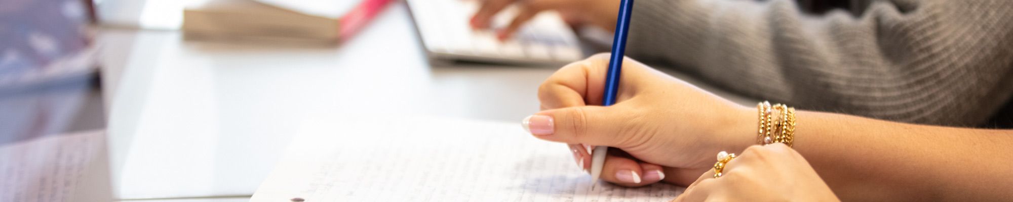 Pen in hand of student writing on a notepad