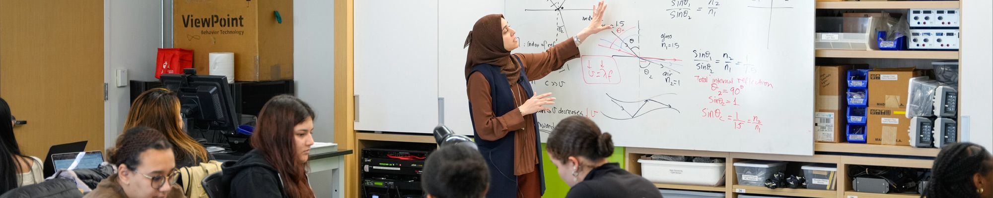 Female student explaining her work on a white board