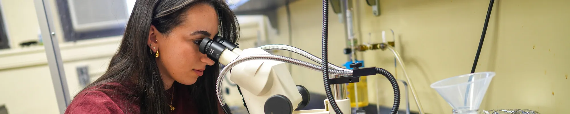Female student looking through a microscope in a lab