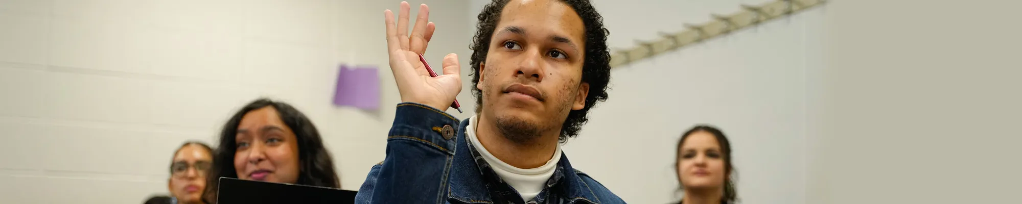 A male student raises hand to ask a question in class
