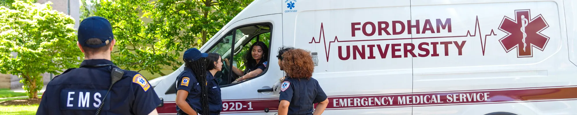 Fordham EMS student members talk next to an ambulance