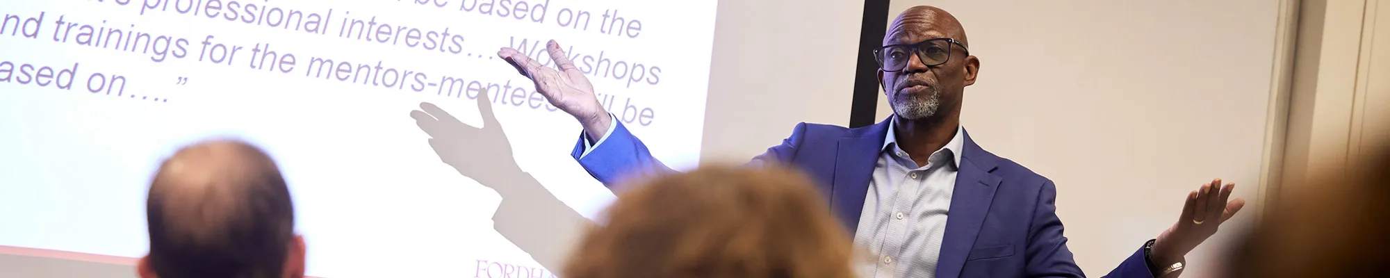 Male professor delivers a lecture and slide presentation to a class