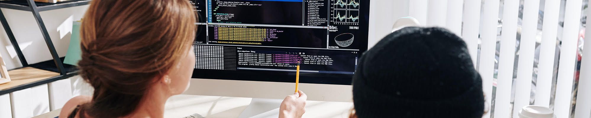 Two students reviewing code on a desktop screen