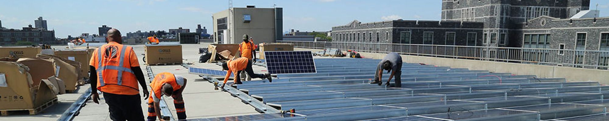 Workers install solar panels on the roof of a parking garage at Rose Hill