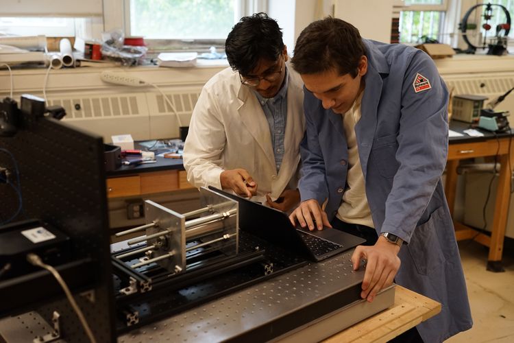 Two students investigate a rocket engine in a physics lab at Fordham