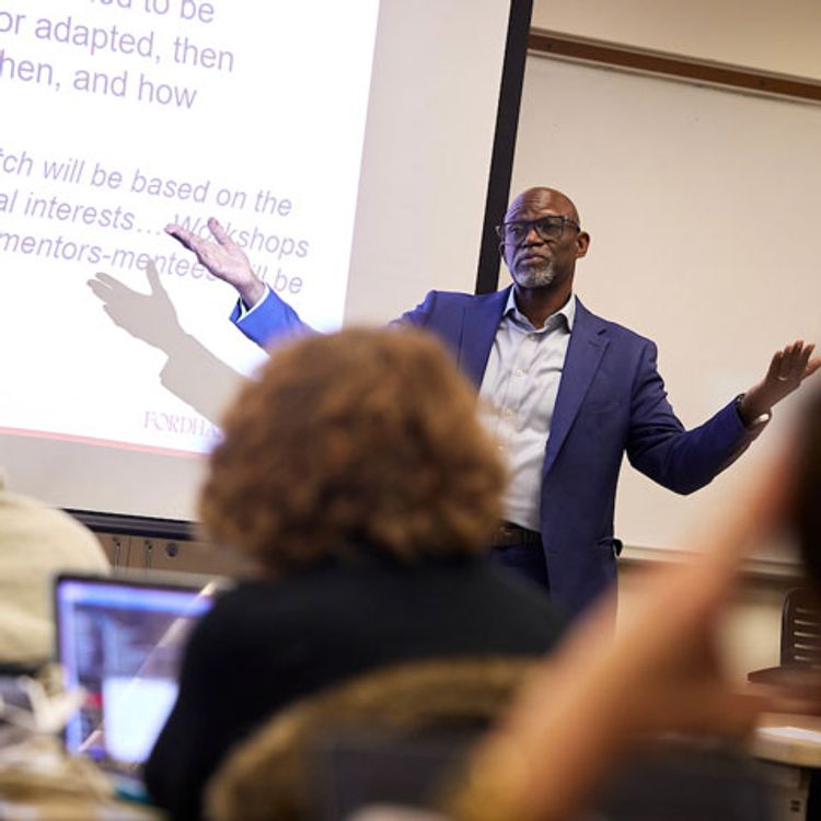 Graduate School of Social Work Professor, Dr. Larry Farmer, lectures in front of class with slide behind him.
