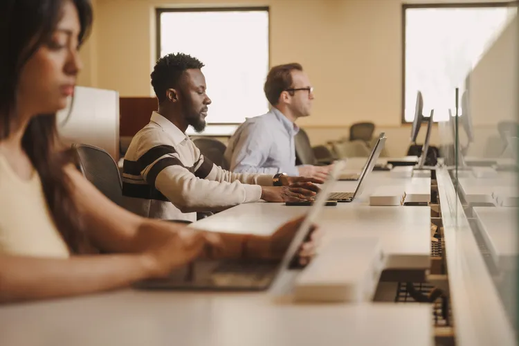 Three students on laptops in classroom