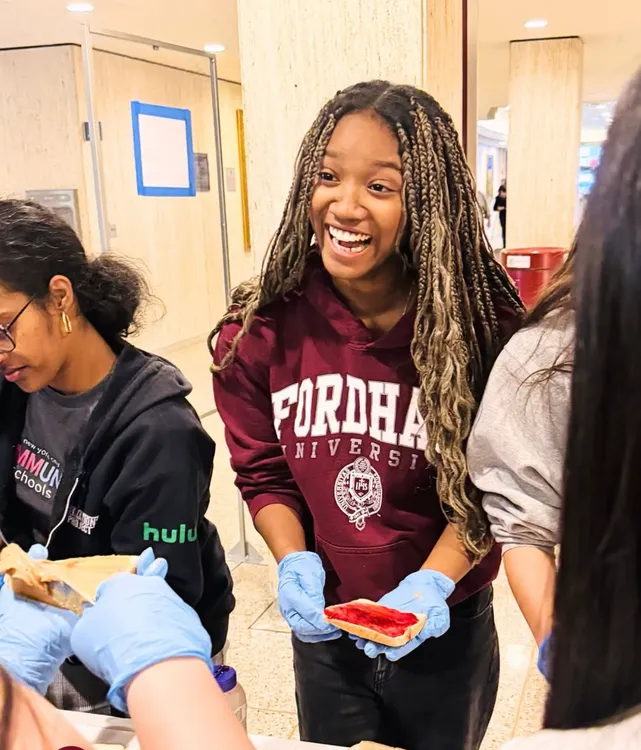 A student smiles while making a sandwich at PAV event