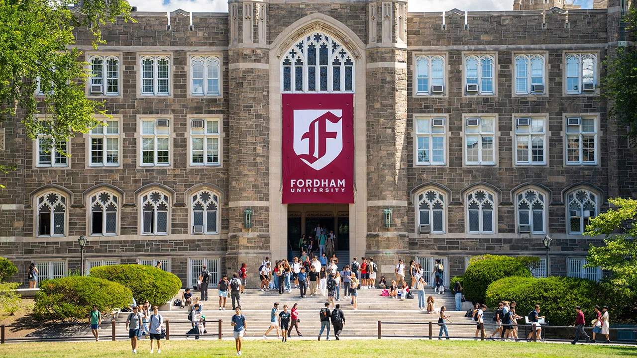 Front facade of Keating Hall with Gothic F banner and students coming down stairs
