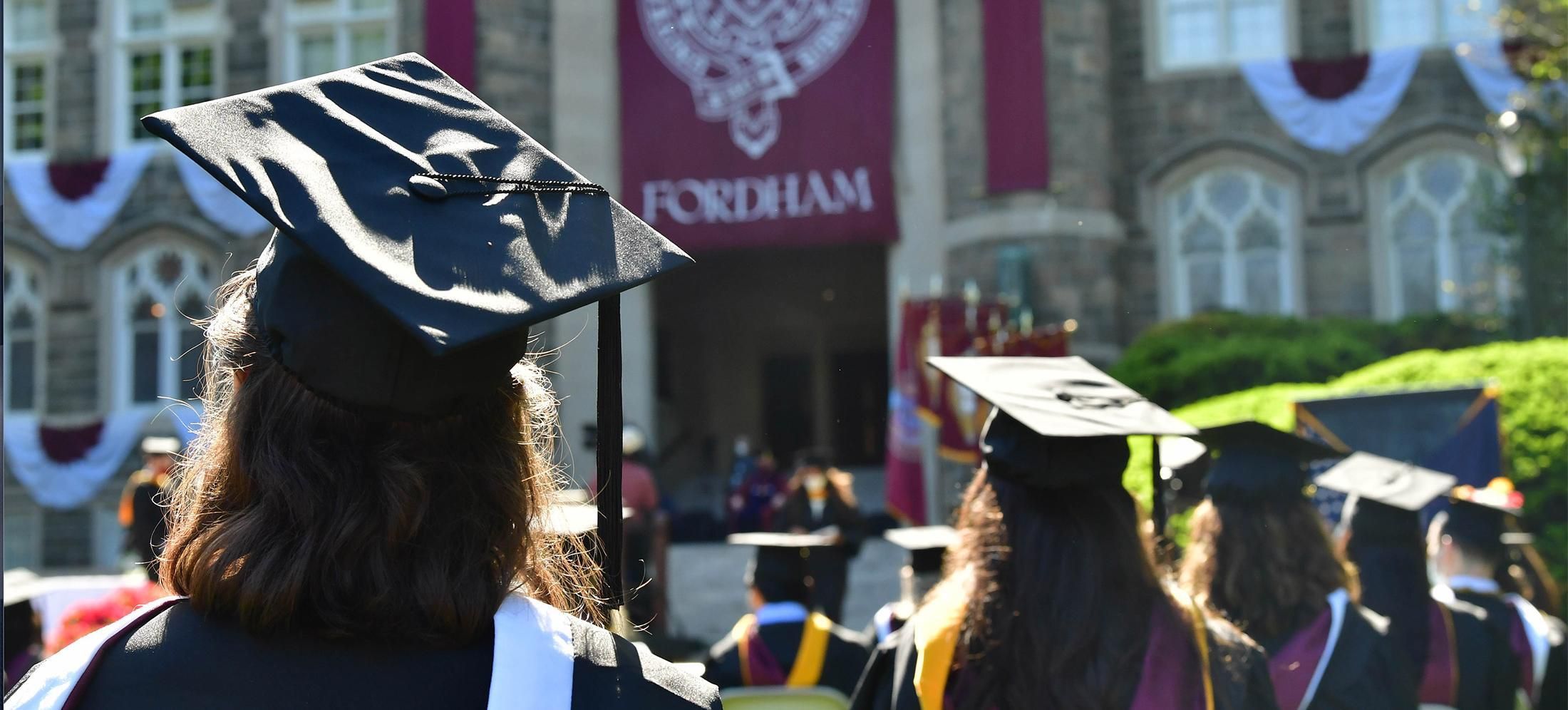 Students sitting with their graduate caps in front of Keating Hall