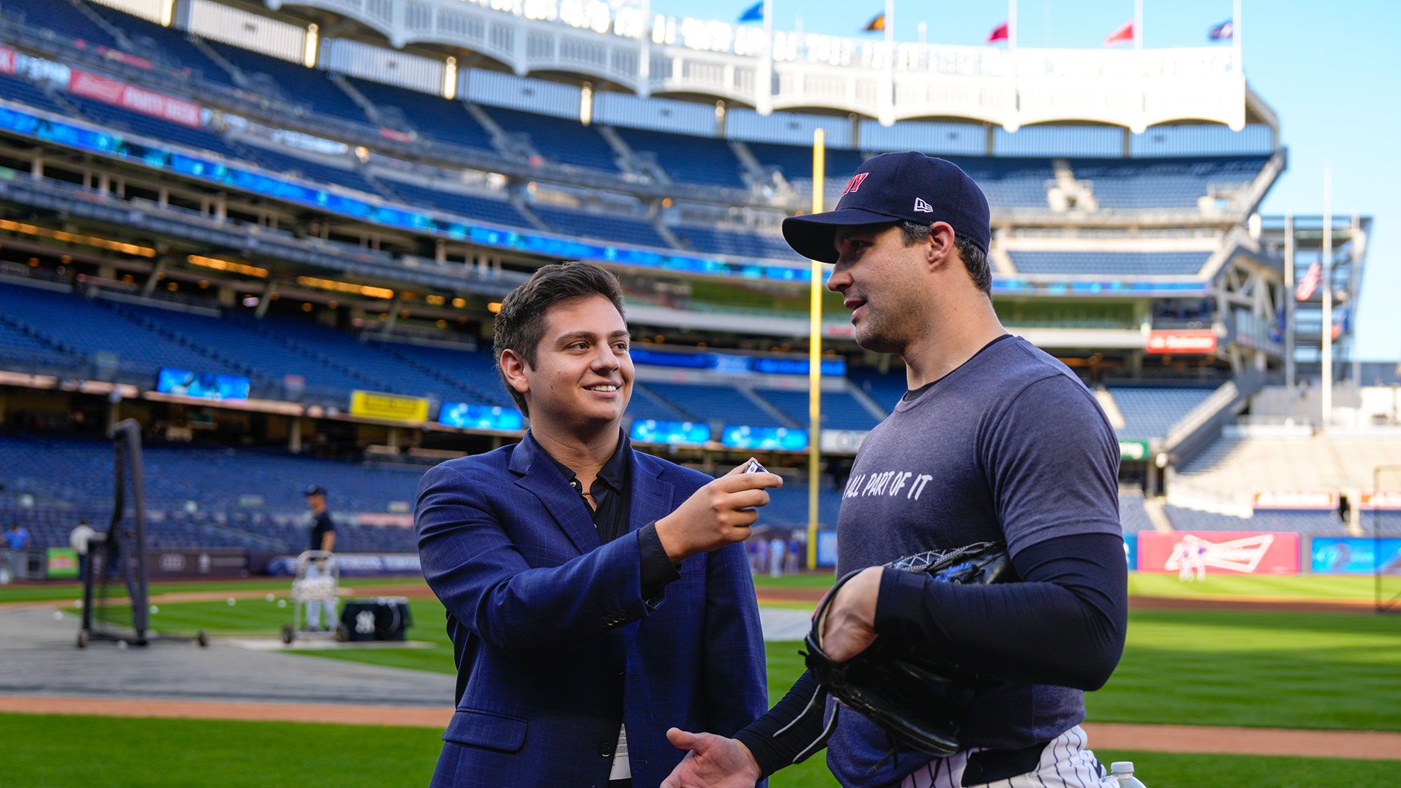 A student interviews a member of the New York Yankees on the field.