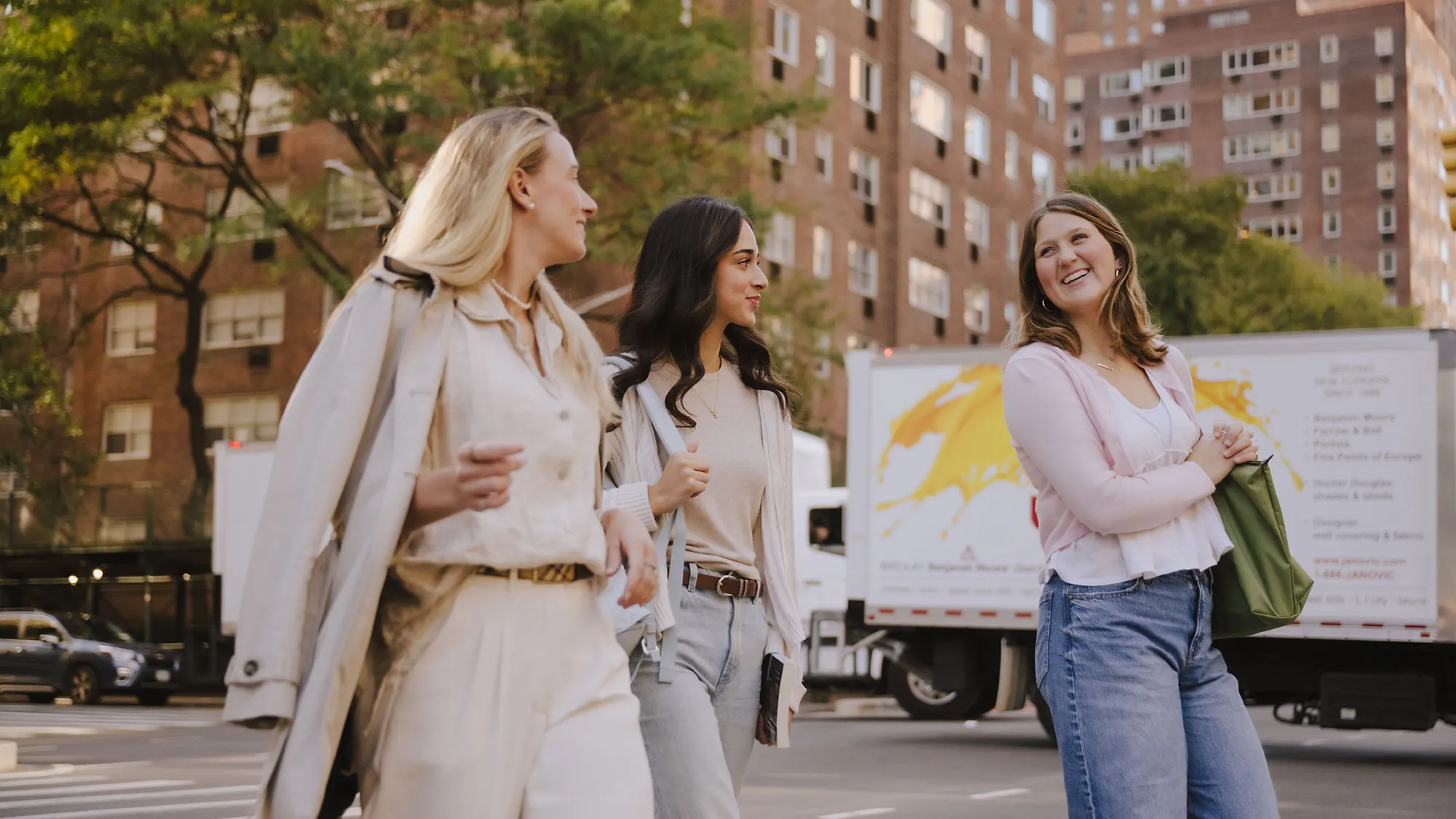 Three students chat and walk across the street