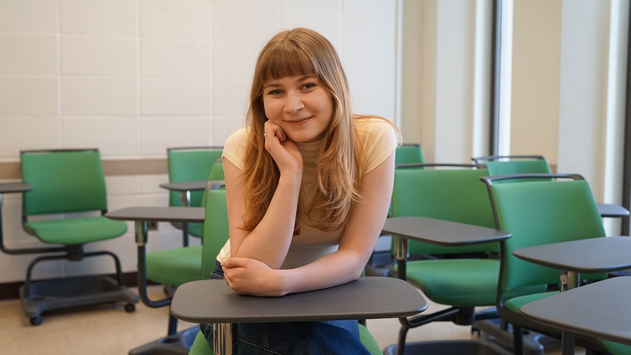 A student poses in a clasroom