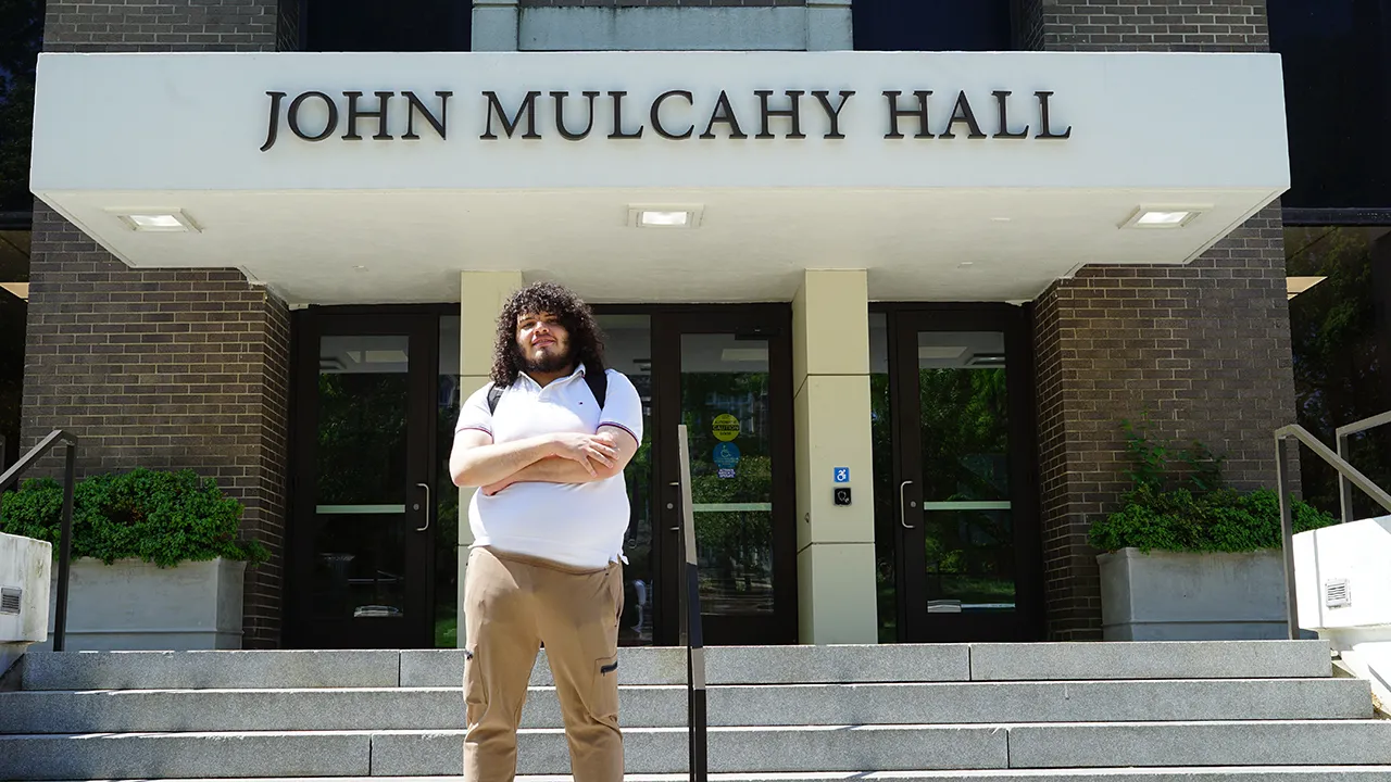 A student poses in front of a building