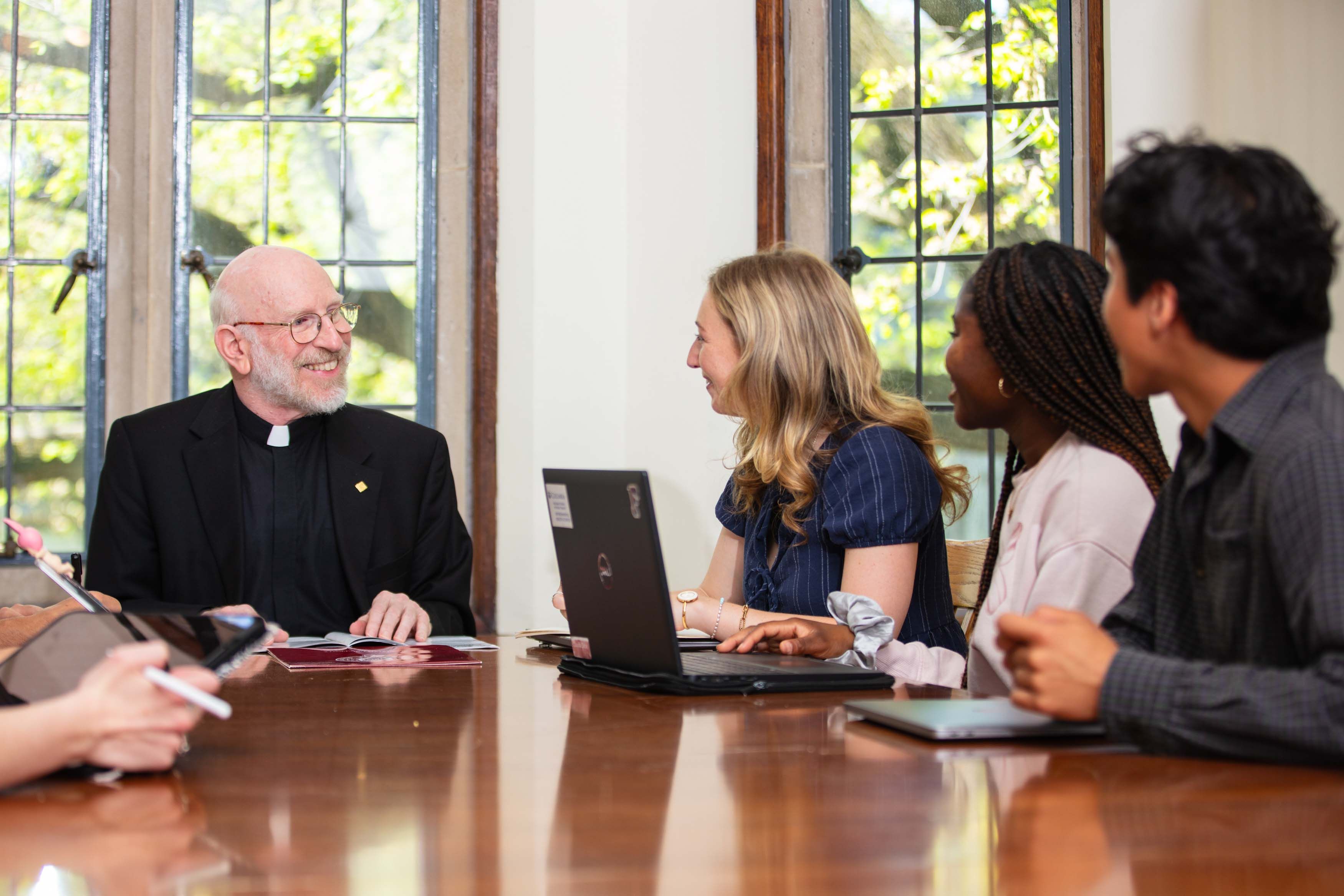 students sitting in class talking to priest