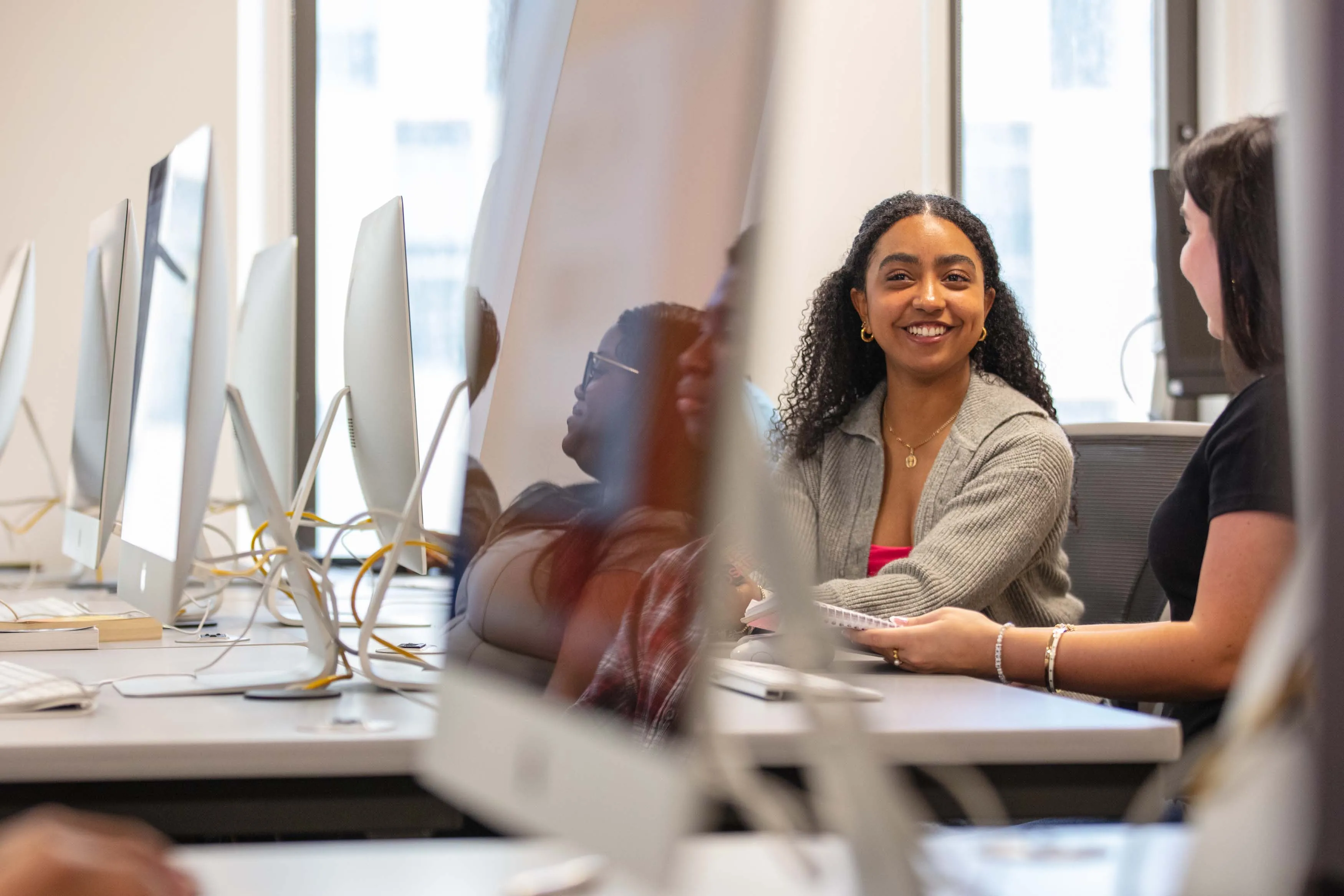 two female students smiling at computers