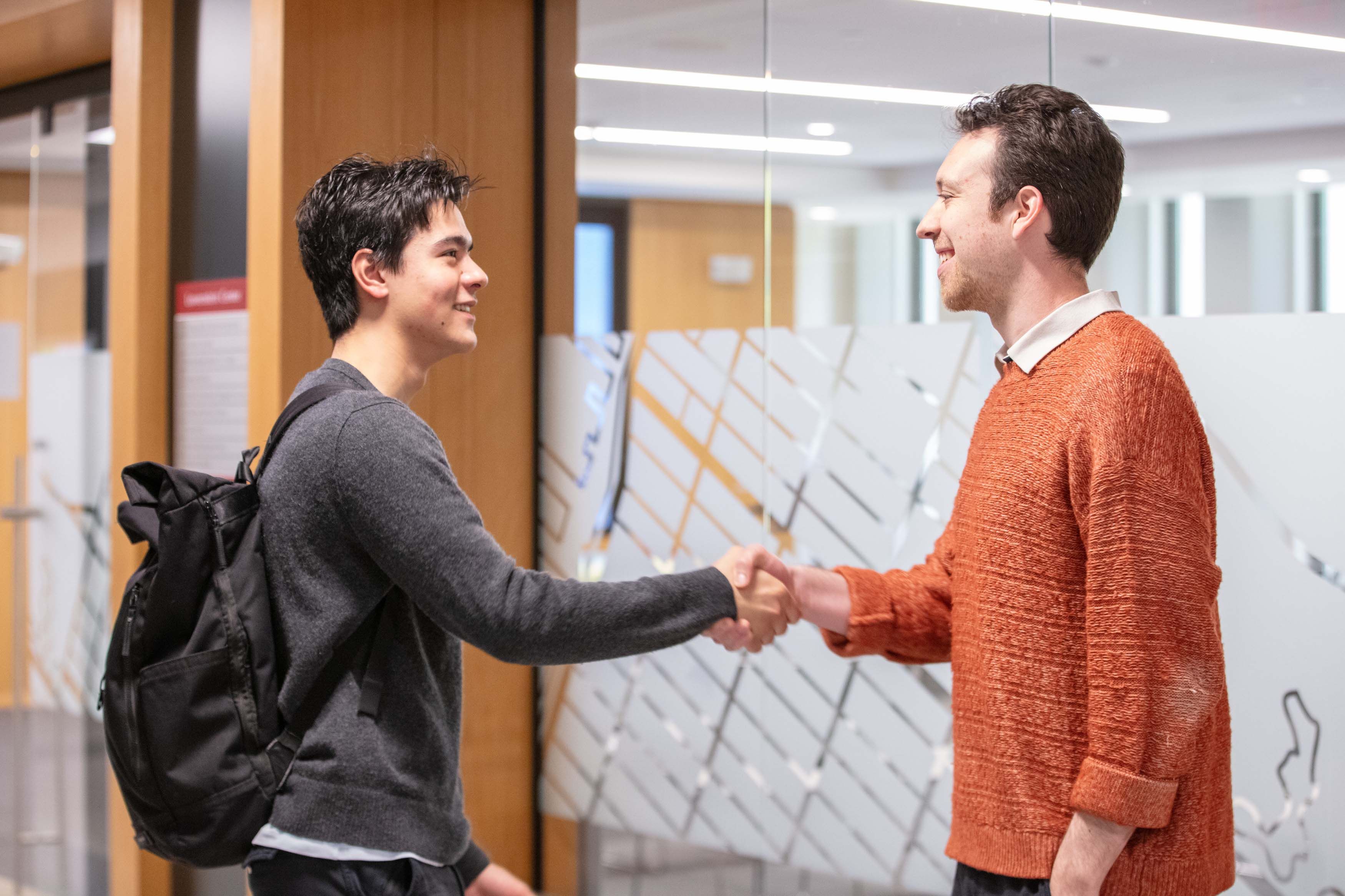 two males shaking hands in front of classroom