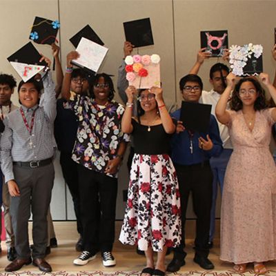 High school students at Fordham holding up graduation caps