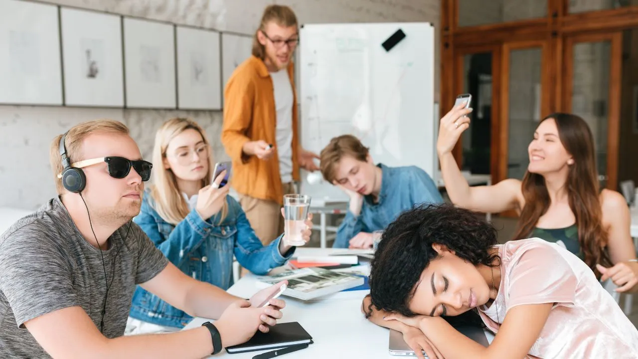 Bored students sit around a table working on a group project