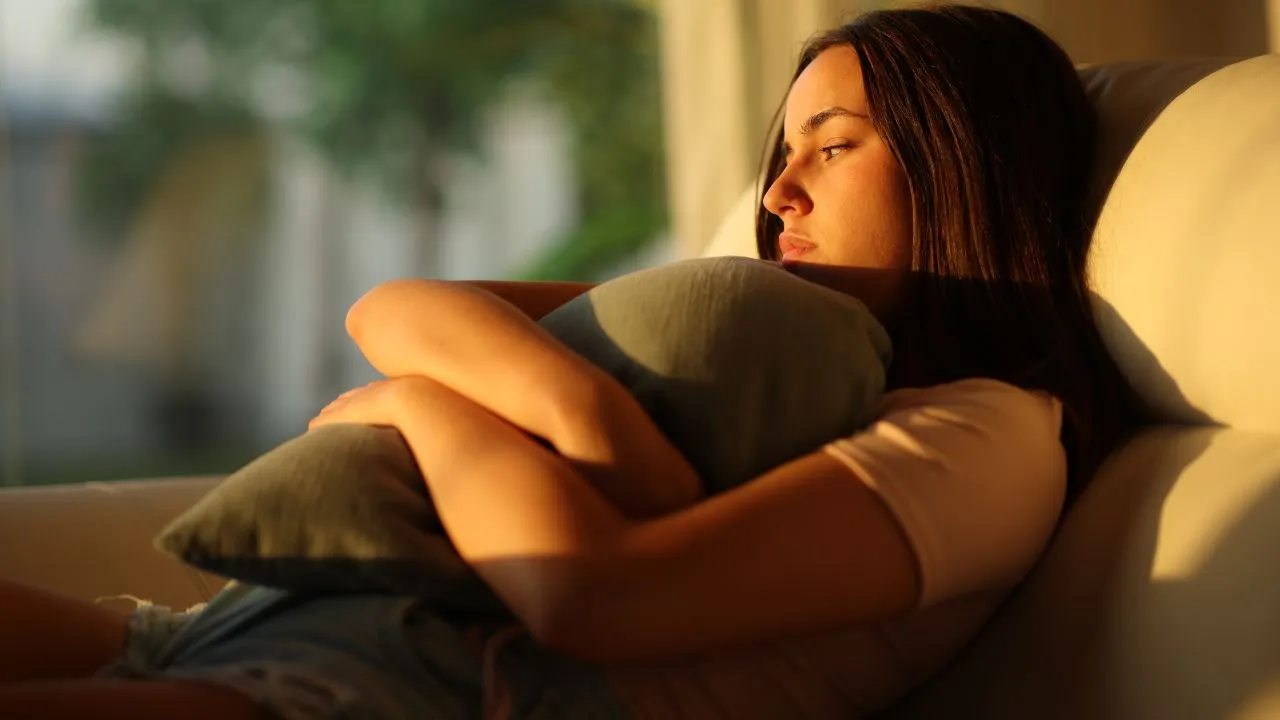 A young woman hugs a pillow