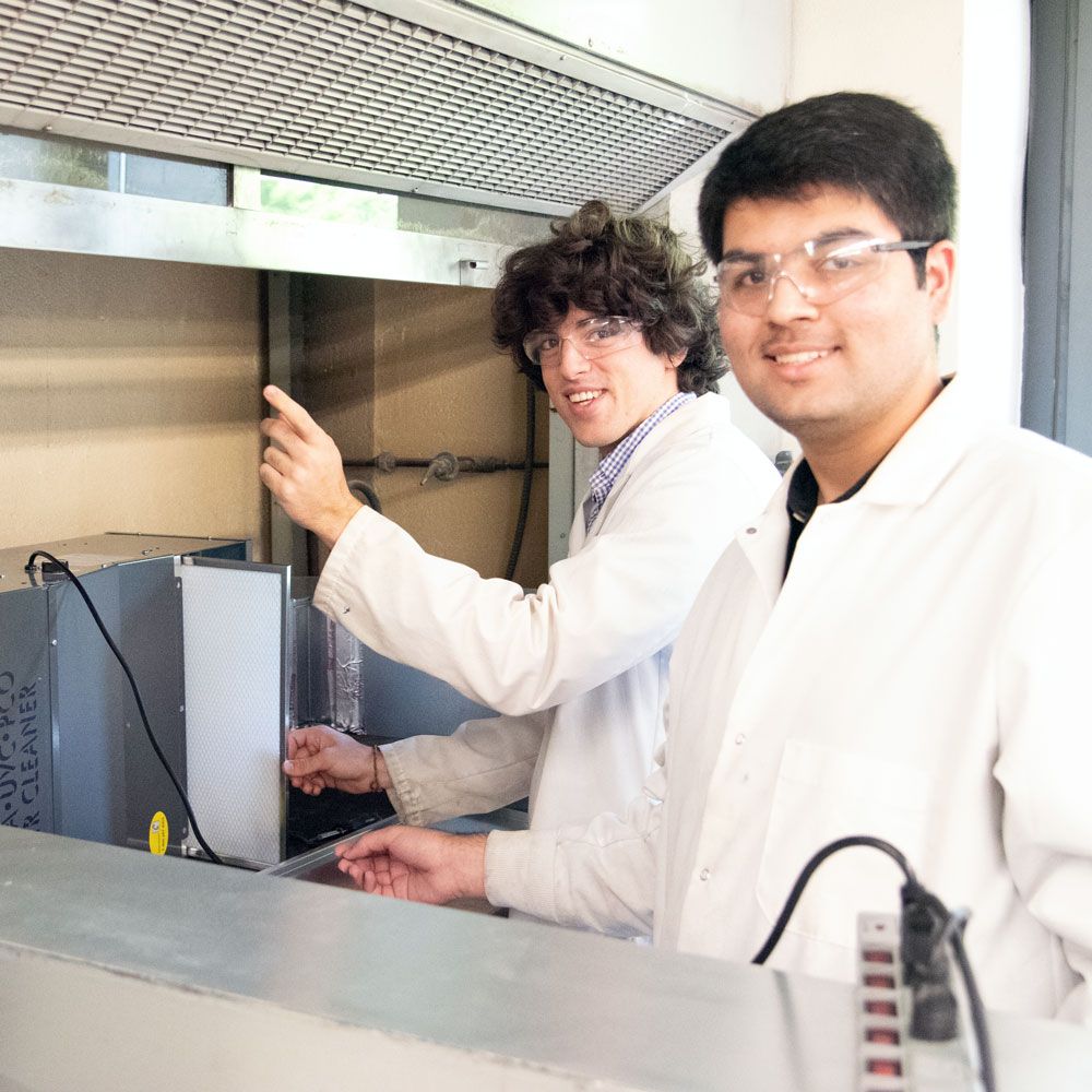 Two students in a lab conduct an experiment that could lead to new types of air purifiers that destroy viruses on a greater scale using nanotechnology