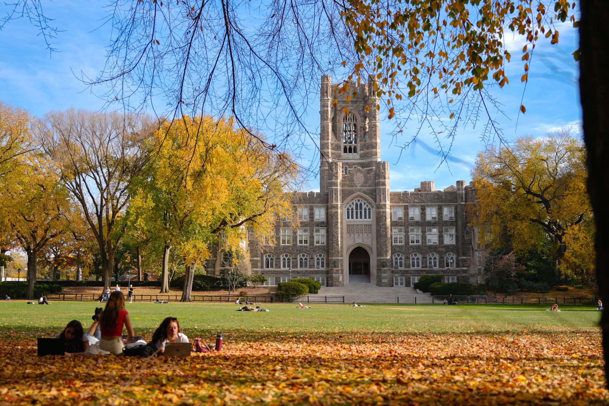 Students study on the grass in front of Keating Hall in the fall