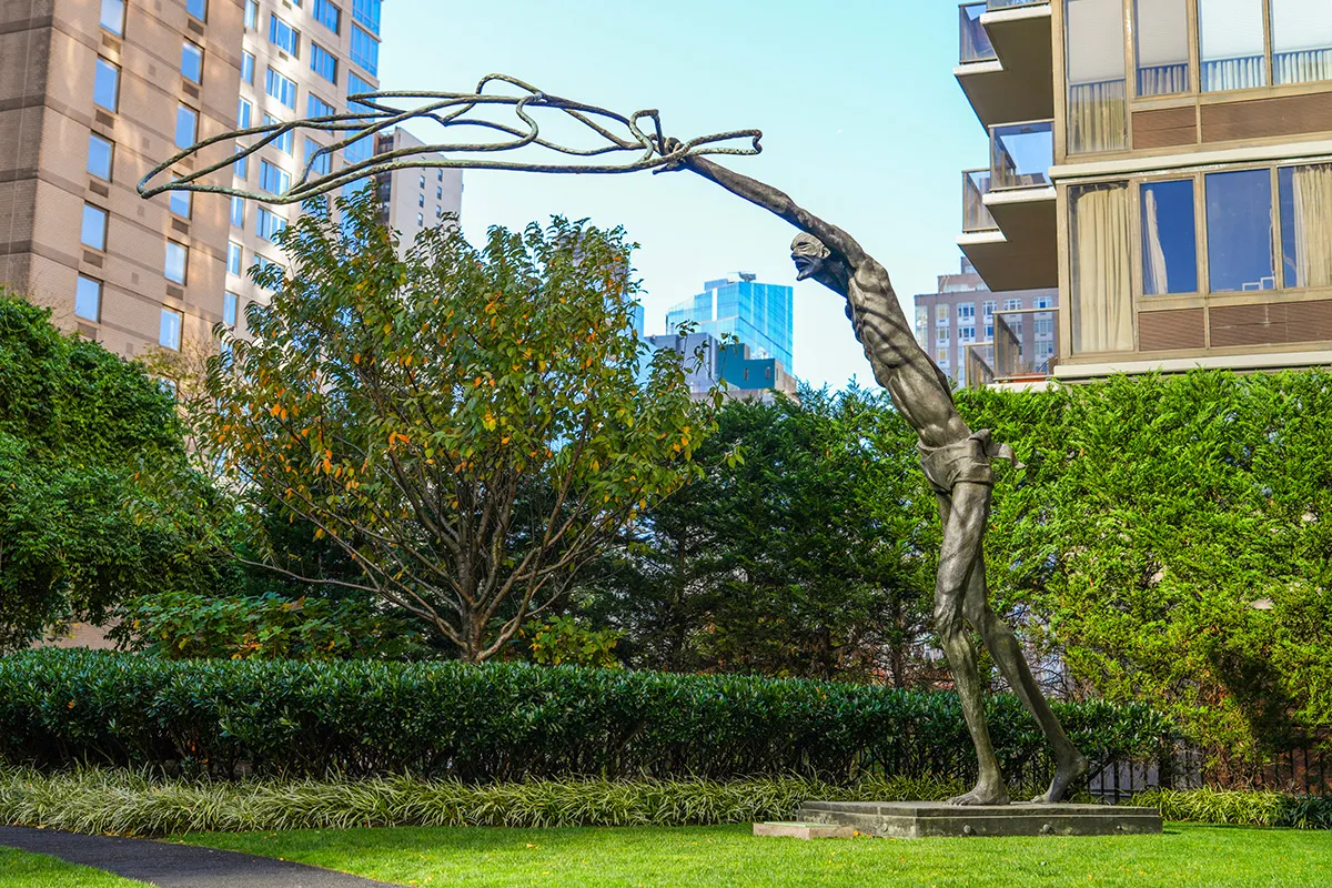 A sculpture of a tall man casting a net for fish