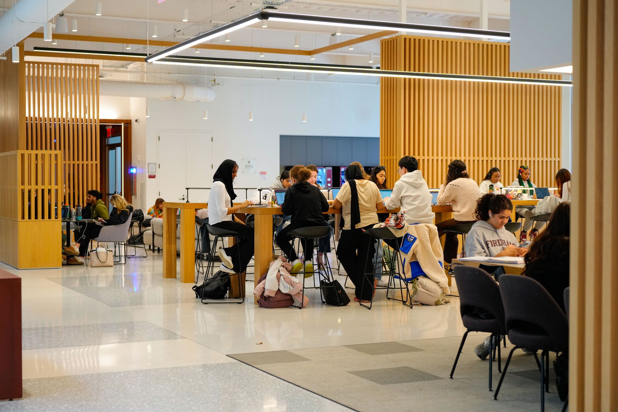 Many students study at a tall communal table in the McShane Center at Rose Hill