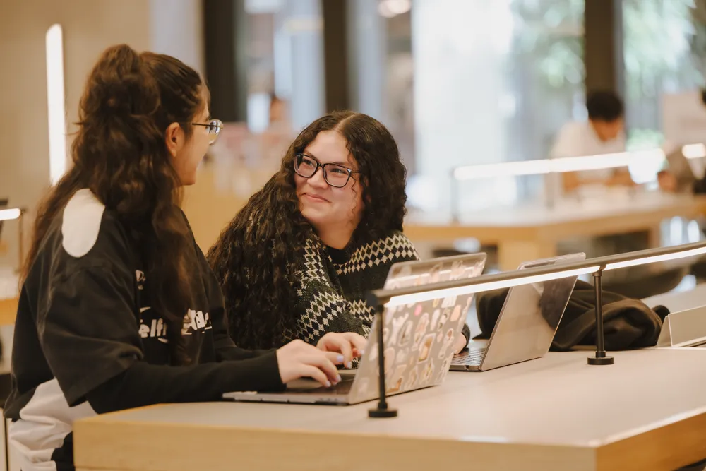 Two students work together in the McShane Center on their laptops