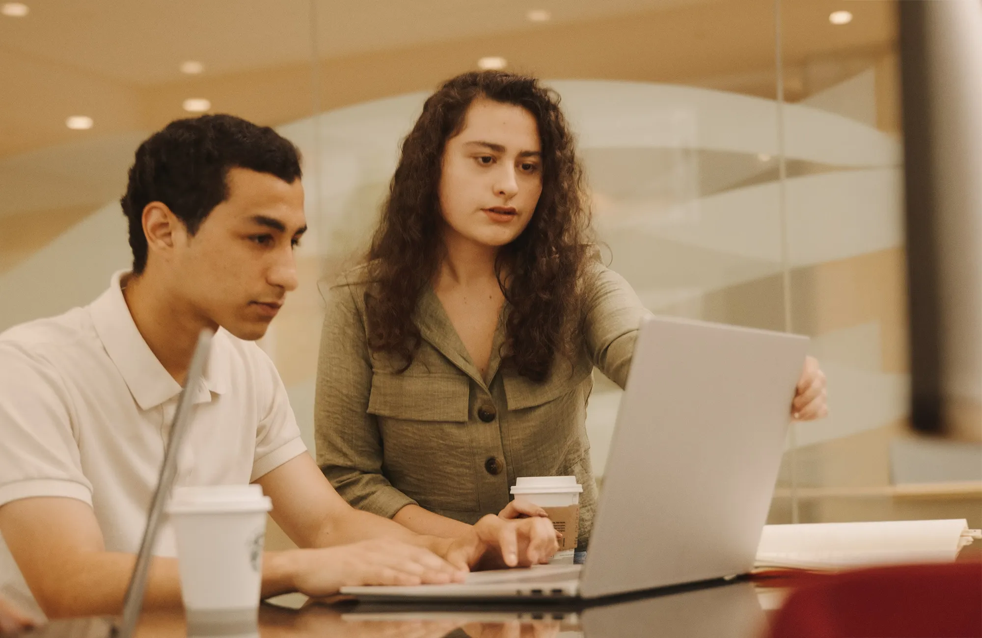 Two students on laptop with coffee cups