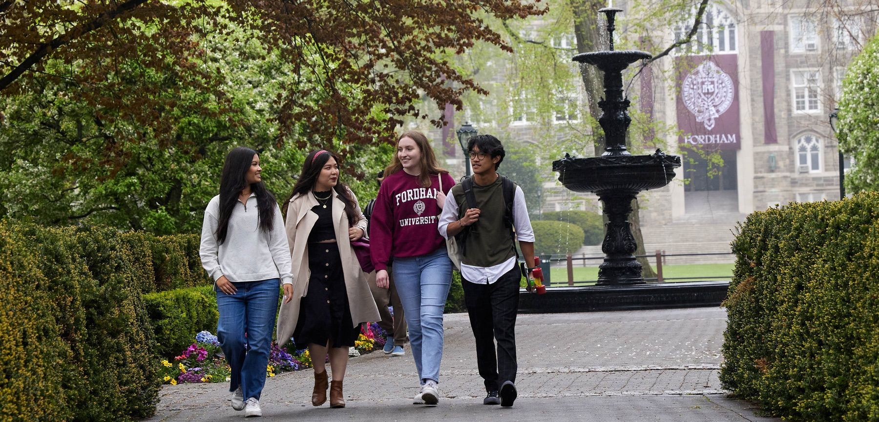 Four students walking and talking on the Rose Hill campus near the fountain