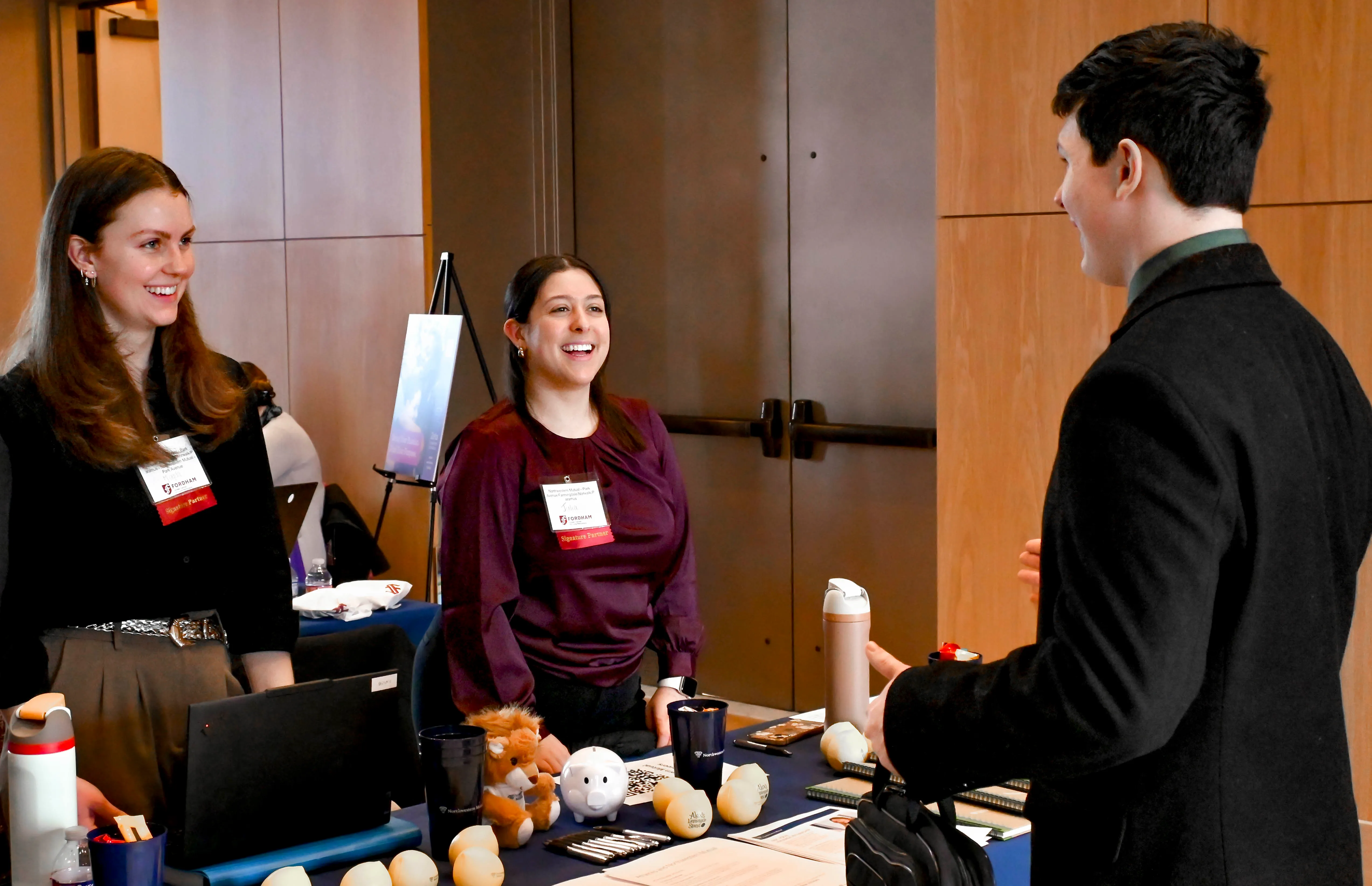 Two employer representatives speak with a student at a tabling event.