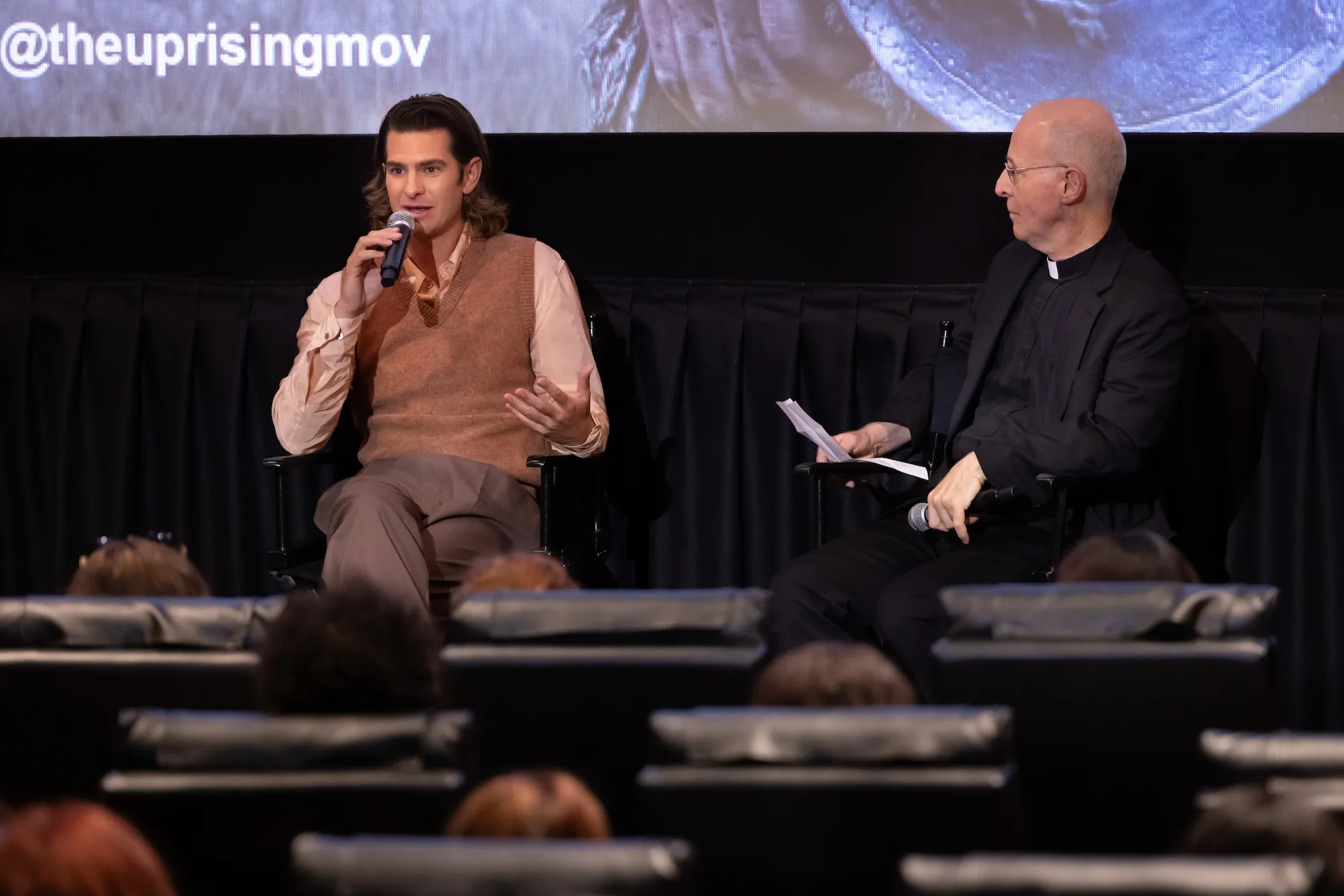 Andrew Garfield and James Martin sit at the front of a movie theatre in conversation
