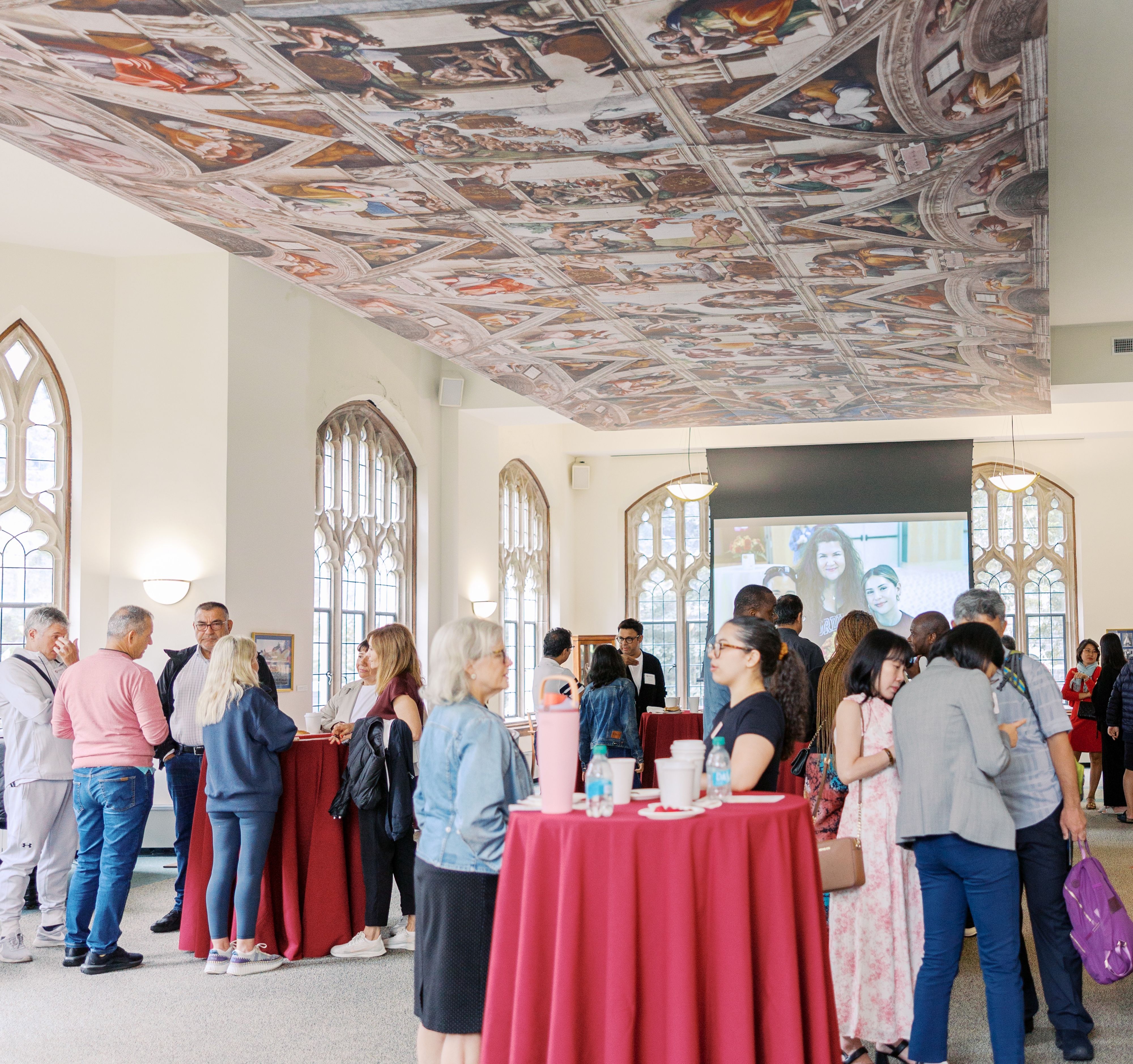Families standing at high top tables in Butler Commons room at Rose Hill campus with ceiling mural