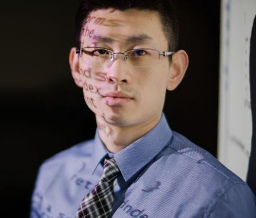 Student standing in front of board in classroom with data reflecting on face