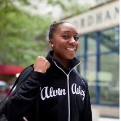 Student walking outside Lincoln Center Campus and smiling