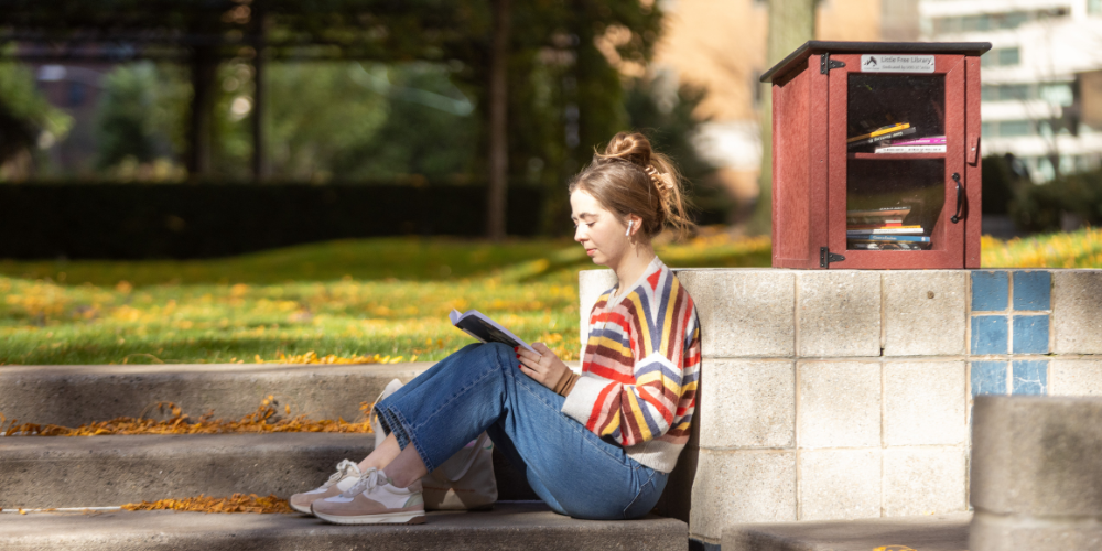 a student sitting in the lincoln center courtyard reading