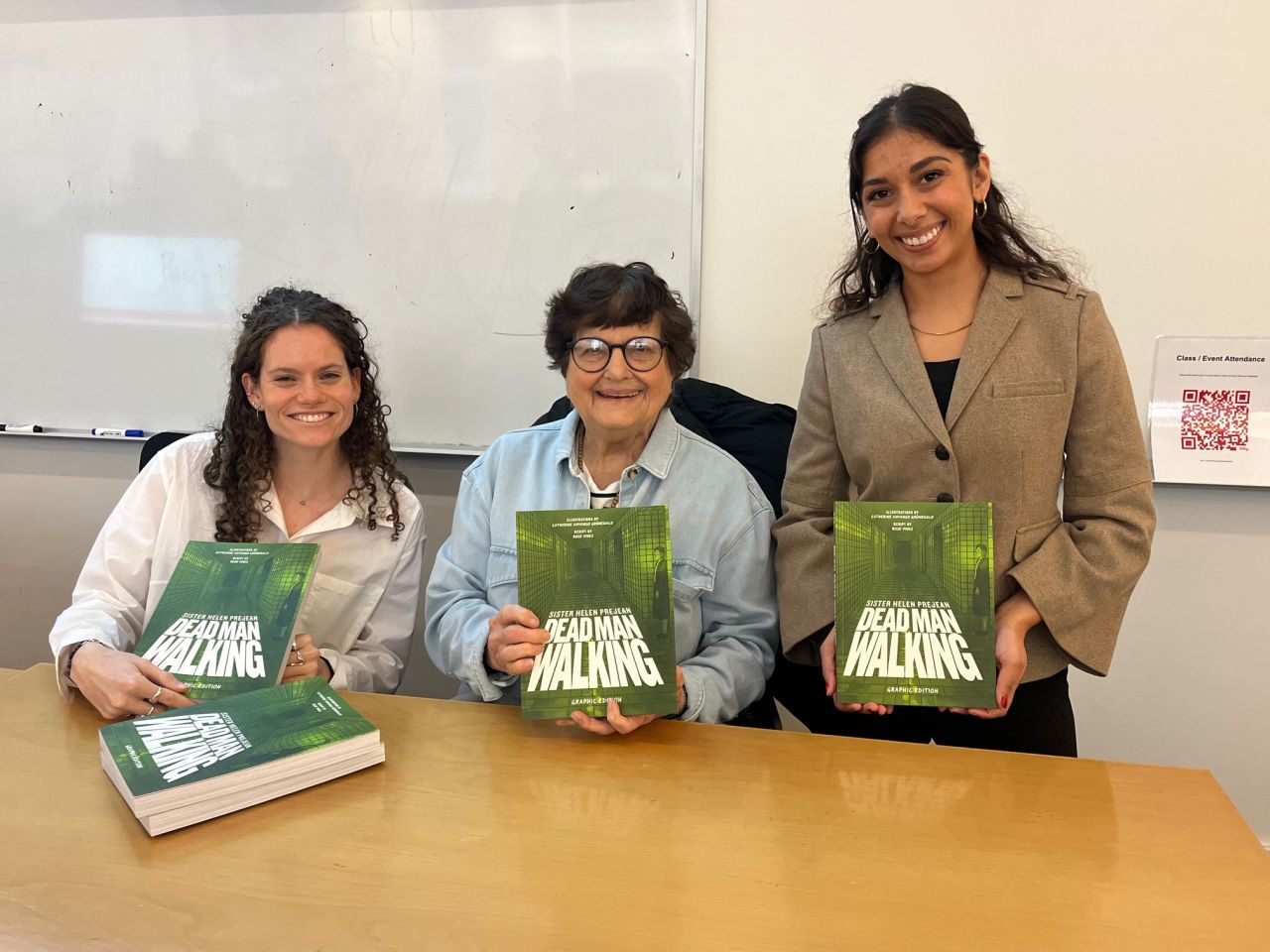 Sister Helen Prejean and students hold copy of Dead Man Walking smiling