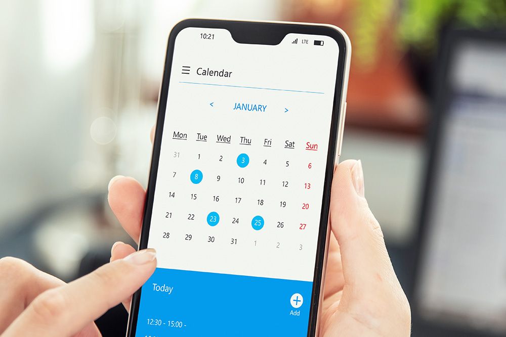 hands holding a phone with calendar app displaying