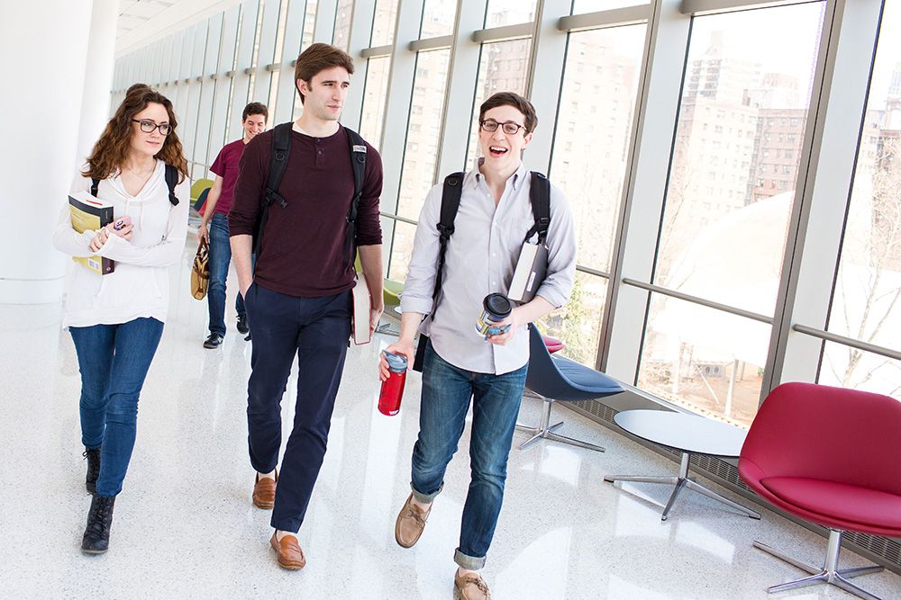 Three law students walking in hallway carrying books